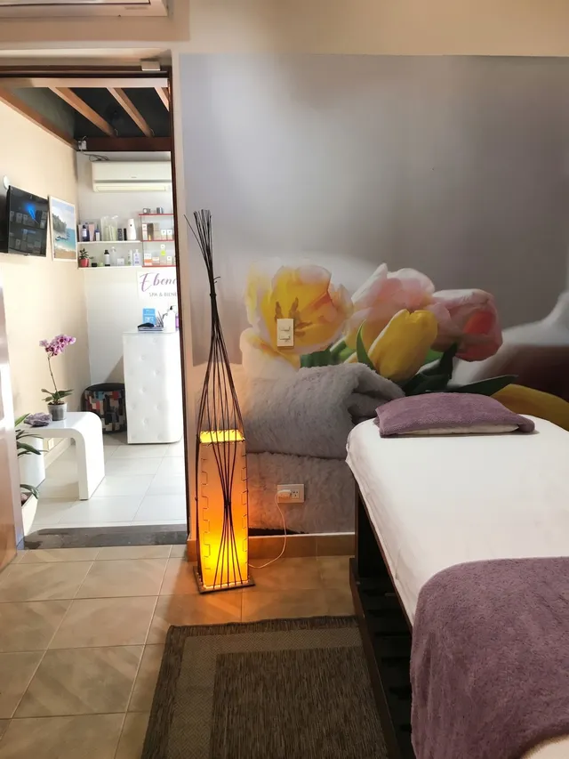 Cabina de tratamientos con camilla, toallas violetas y luz cálida